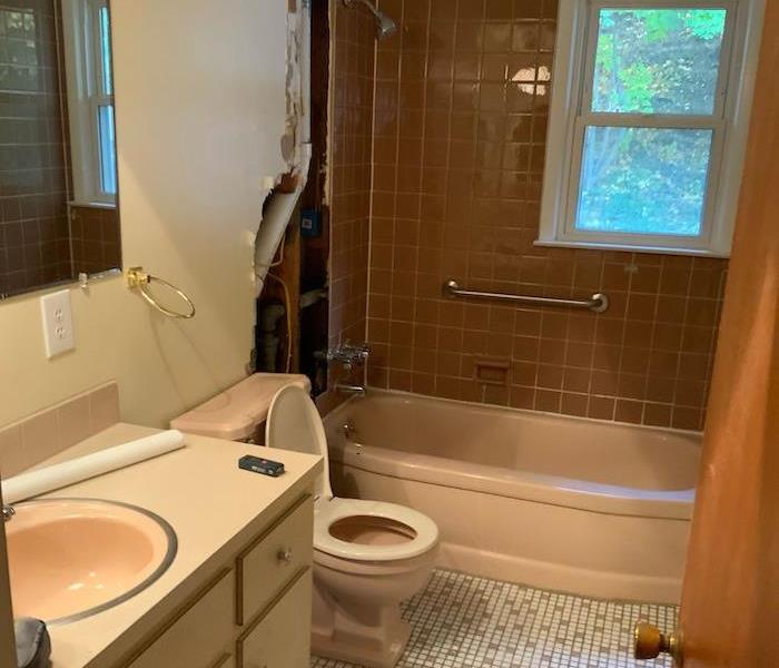 Bathroom with damaged wall and white tile floor