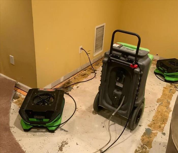 Room with carpet partially removed and SERVPRO drying equipment