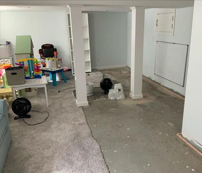 Basement with partially removed carpet and furnishings