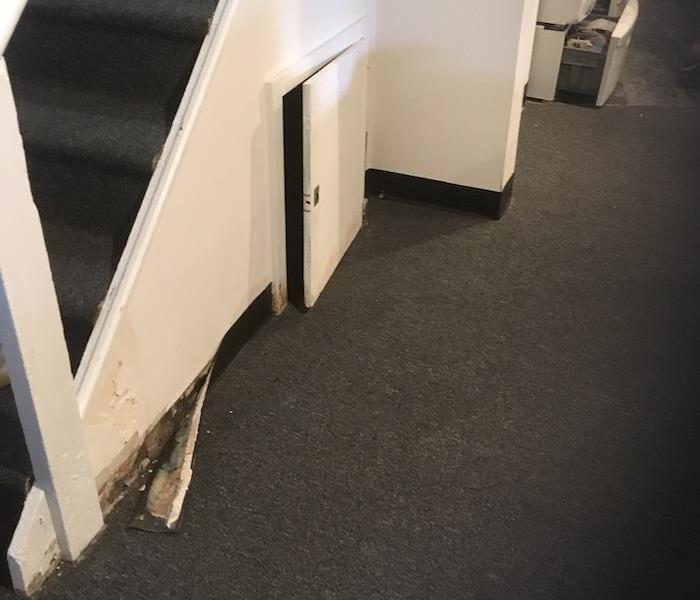 basement with storm damage at the bottom of the staircase