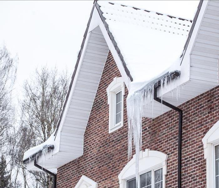 Snow pack on a home with icicles hanging off the roof.